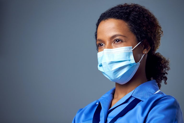 Studio Portrait Of Female Nurse Wearing Uniform And Face Mask